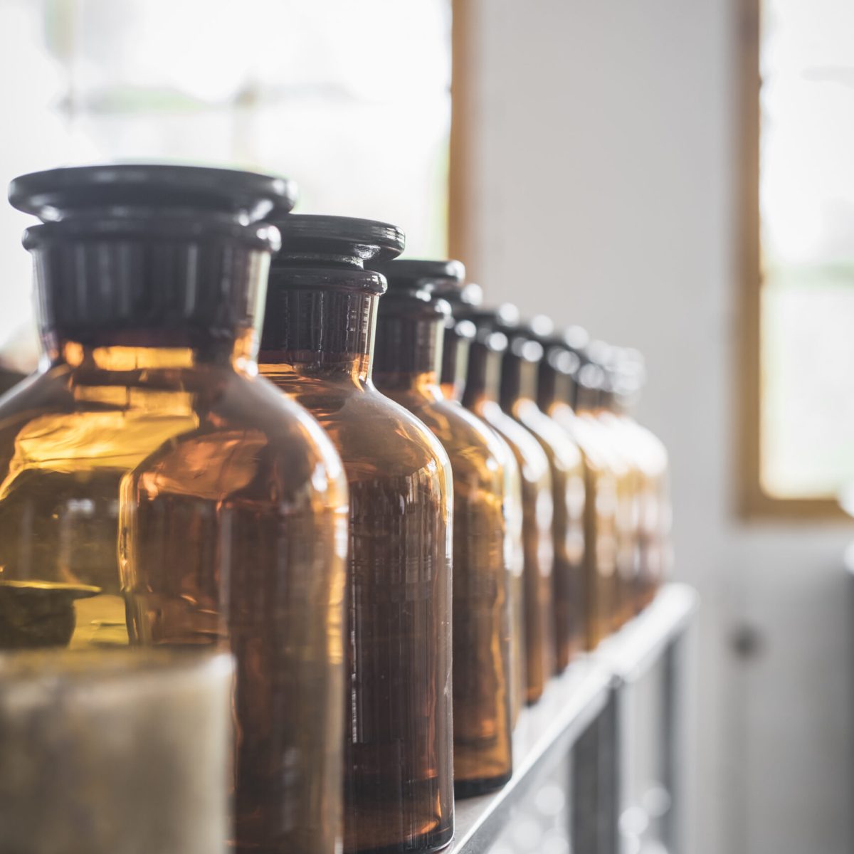 Row of retro glass jars placed on shelf in room on blurred background